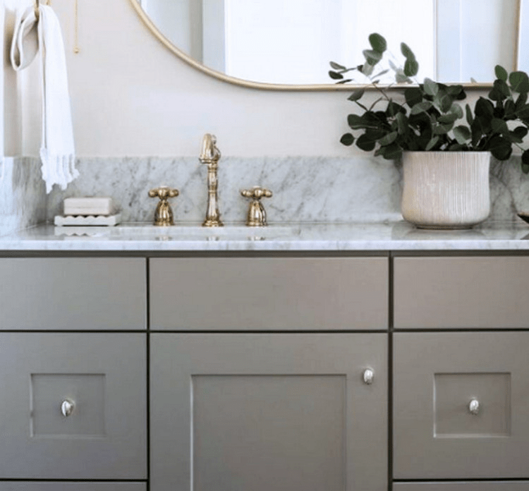Elegant bathroom vanity featuring a marble countertop, golden faucets, and a potted plant, creating a serene and stylish aesthetic.