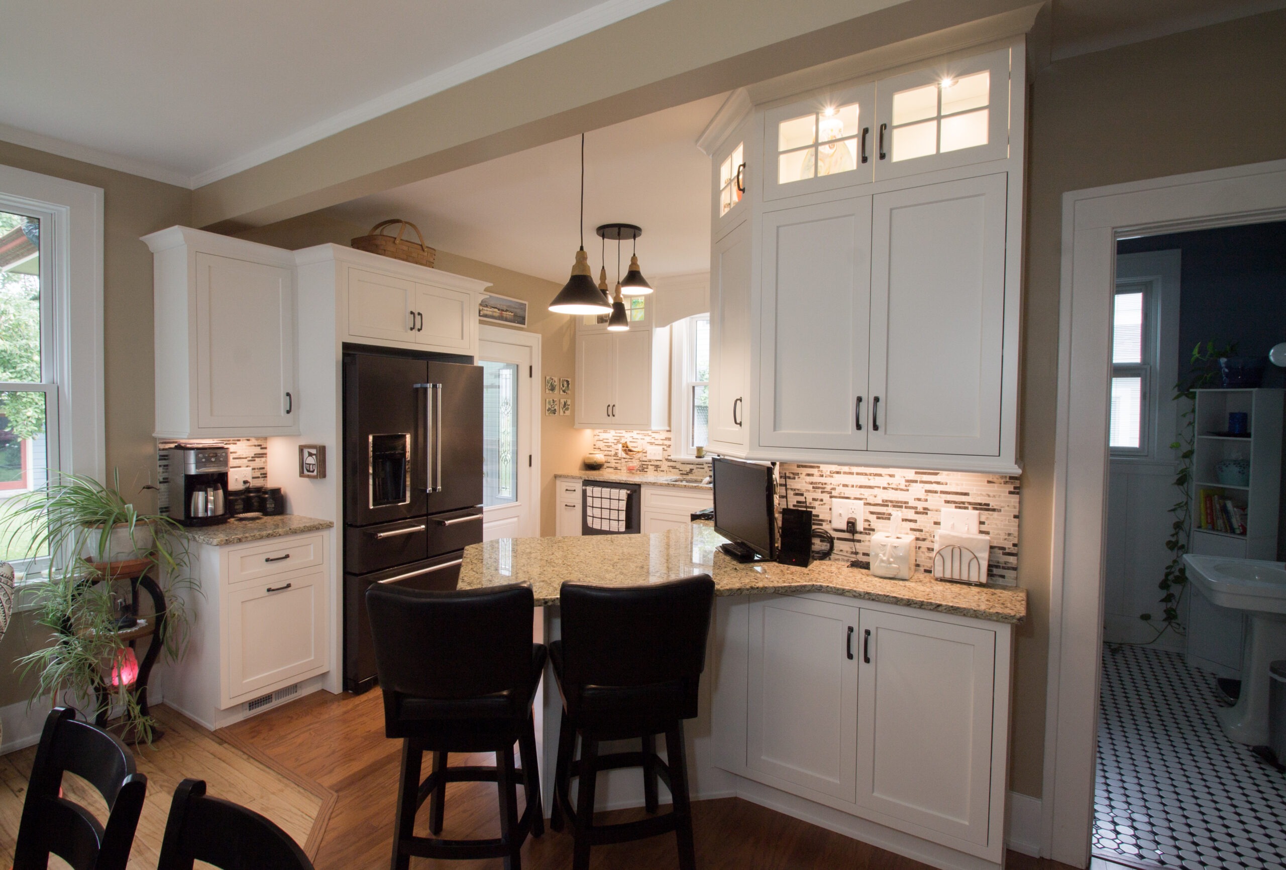 Modern kitchen featuring white cabinetry, granite countertops, and a black refrigerator